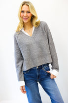 Woman wearing a gray sweater and blue jeans on a white background