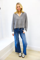woman wearing grey sweater with sequins and white collar, paired with medium wash denim 