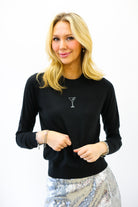 Woman wearing a black sweater with a martini glass design on a white background