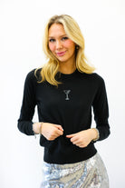 Woman wearing a black long-sleeve top with a martini glass design on a white background