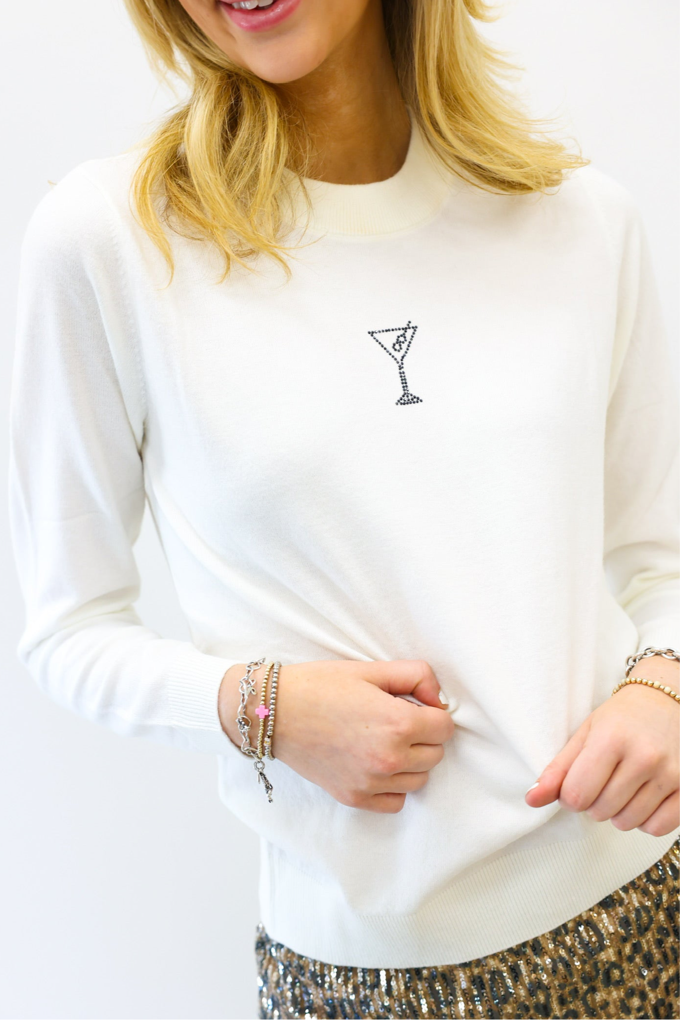 White sweatshirt with a small design on the chest, worn by a person.