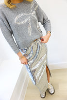 Person wearing a gray sweater with sequin design and a silver sequin skirt.