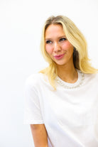 Woman with blonde hair wearing a white shirt against a white background