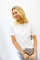 Woman wearing a white t-shirt with a brand logo on a plain background