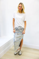 Woman wearing a white top and silver metallic skirt against a white background