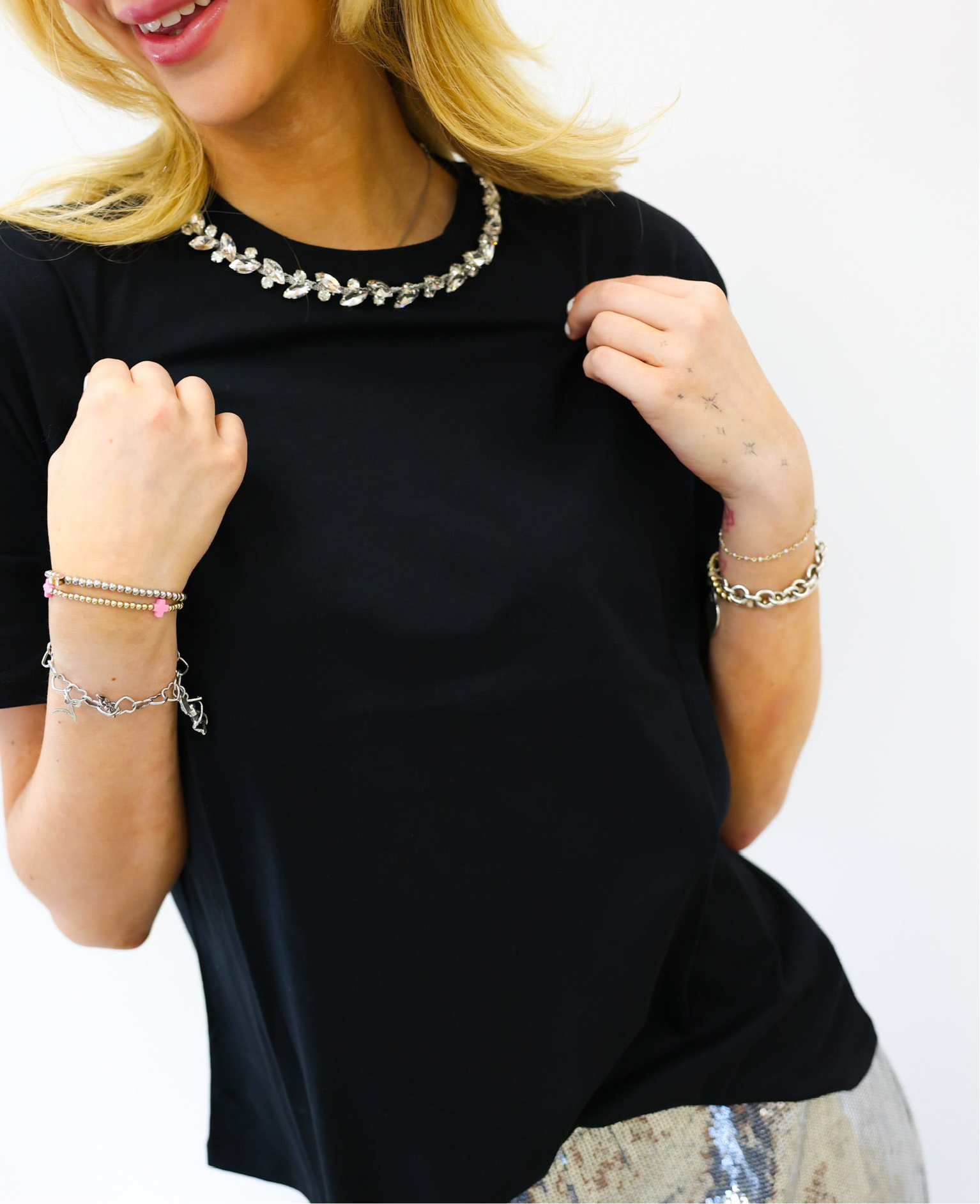 Woman wearing a black top with jewelry on a white background