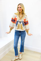 Woman wearing a colorful sweater and blue jeans against a white background
