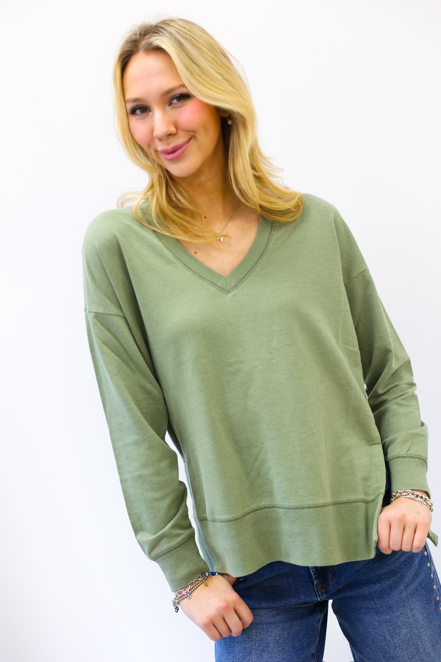 Woman wearing a green sweater and blue jeans on a white background