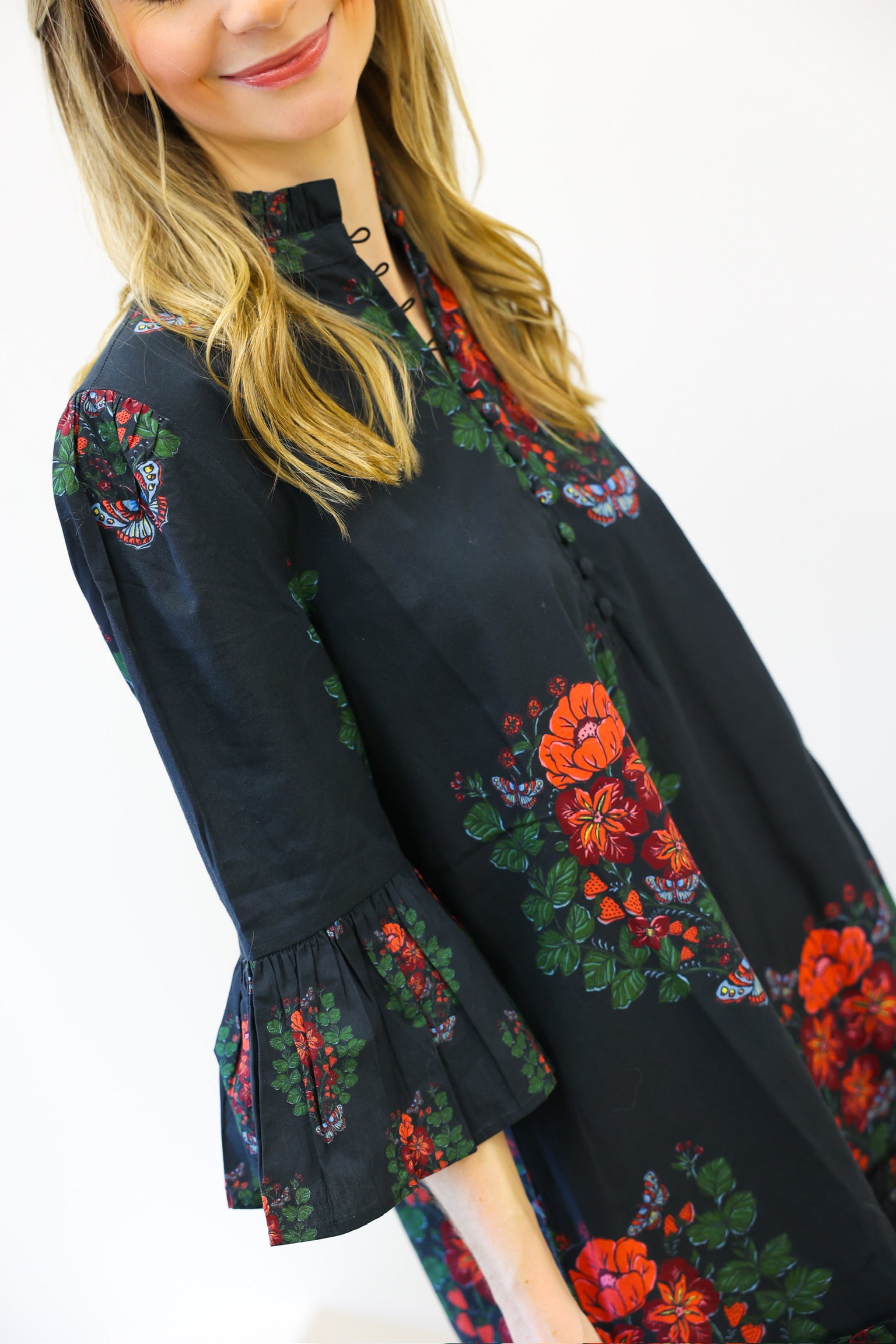 Woman wearing a black dress with colorful floral embroidery on a white background