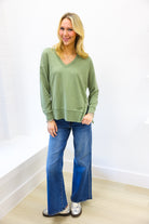 Woman wearing a green sweater and blue jeans against a white background
