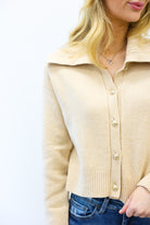 Beige cardigan worn by a person on a white background