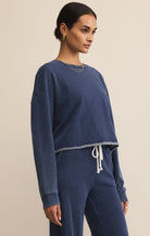 Woman wearing a blue sweatshirt and pants against a beige background