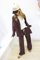 Person wearing a brown outfit with a white and black cap indoors.
