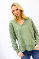Woman wearing a green sweater and blue jeans on a white background