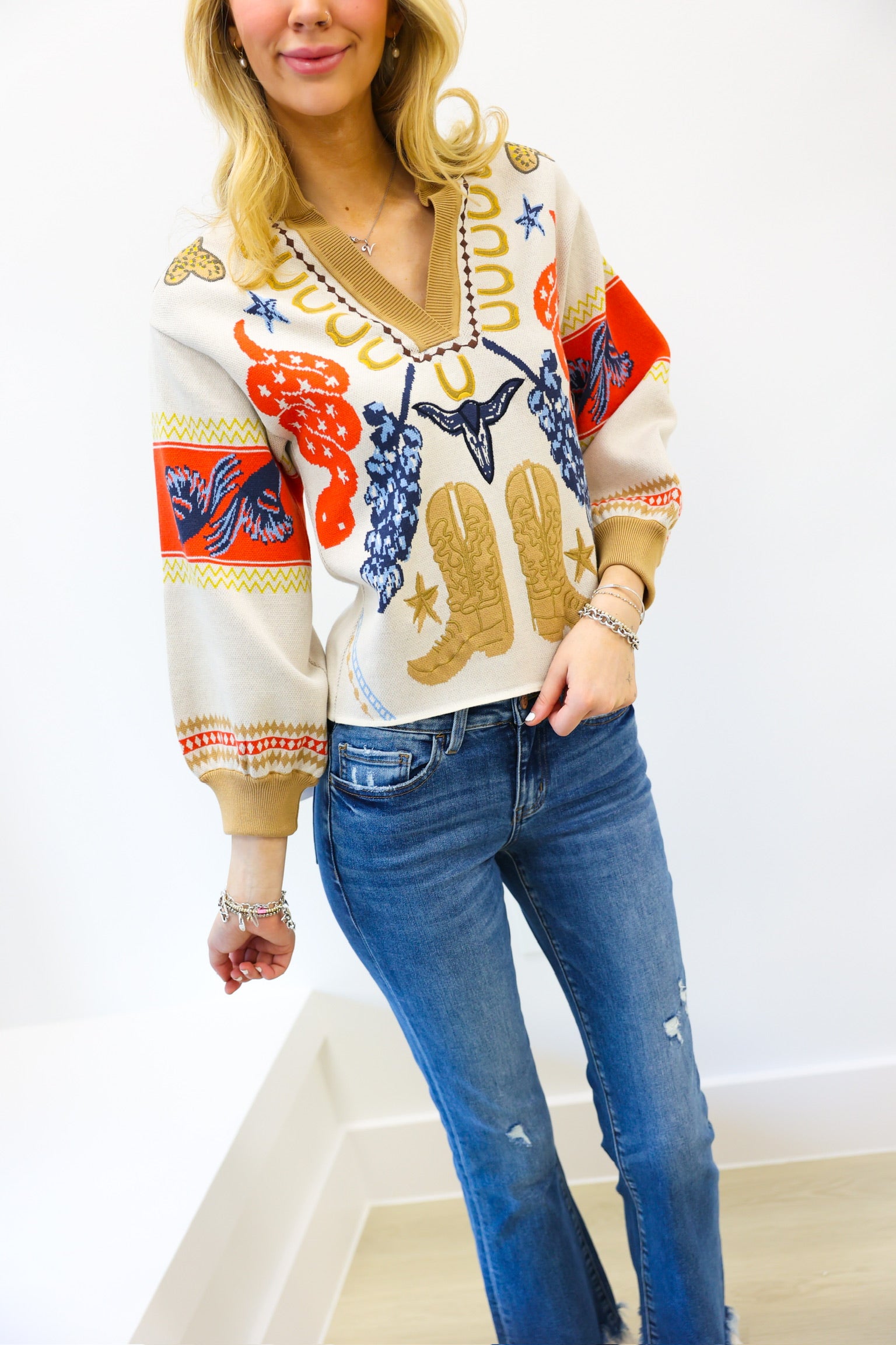 Woman wearing a colorful patterned sweater and blue jeans on a white background
