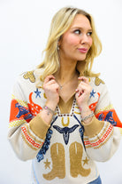 Woman wearing a colorful sweater with cowboy boot designs on a white background