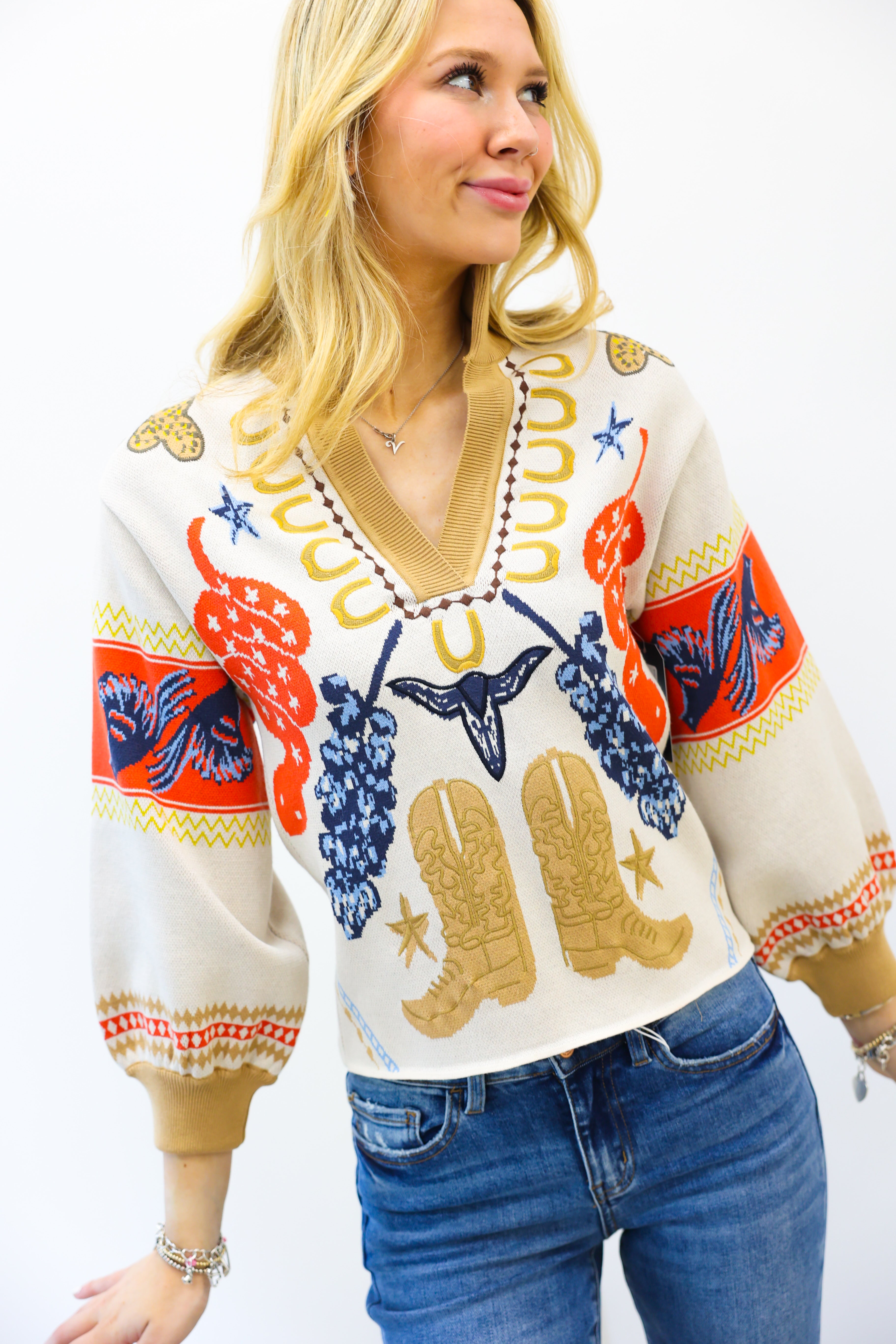 Woman wearing a colorful patterned sweater with cowboy boots and grapes on a white background
