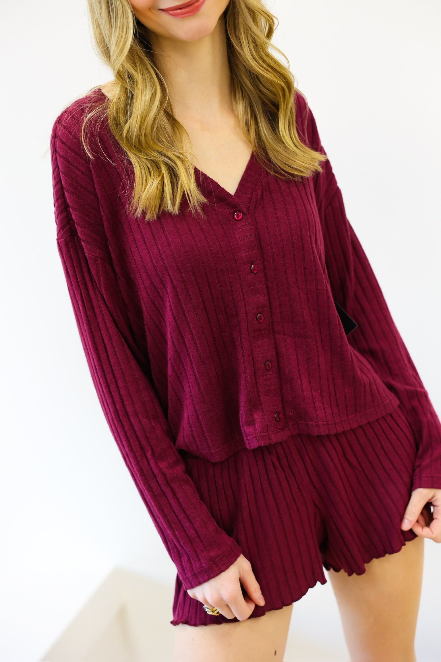 Woman wearing a burgundy ribbed lounge set on a white background