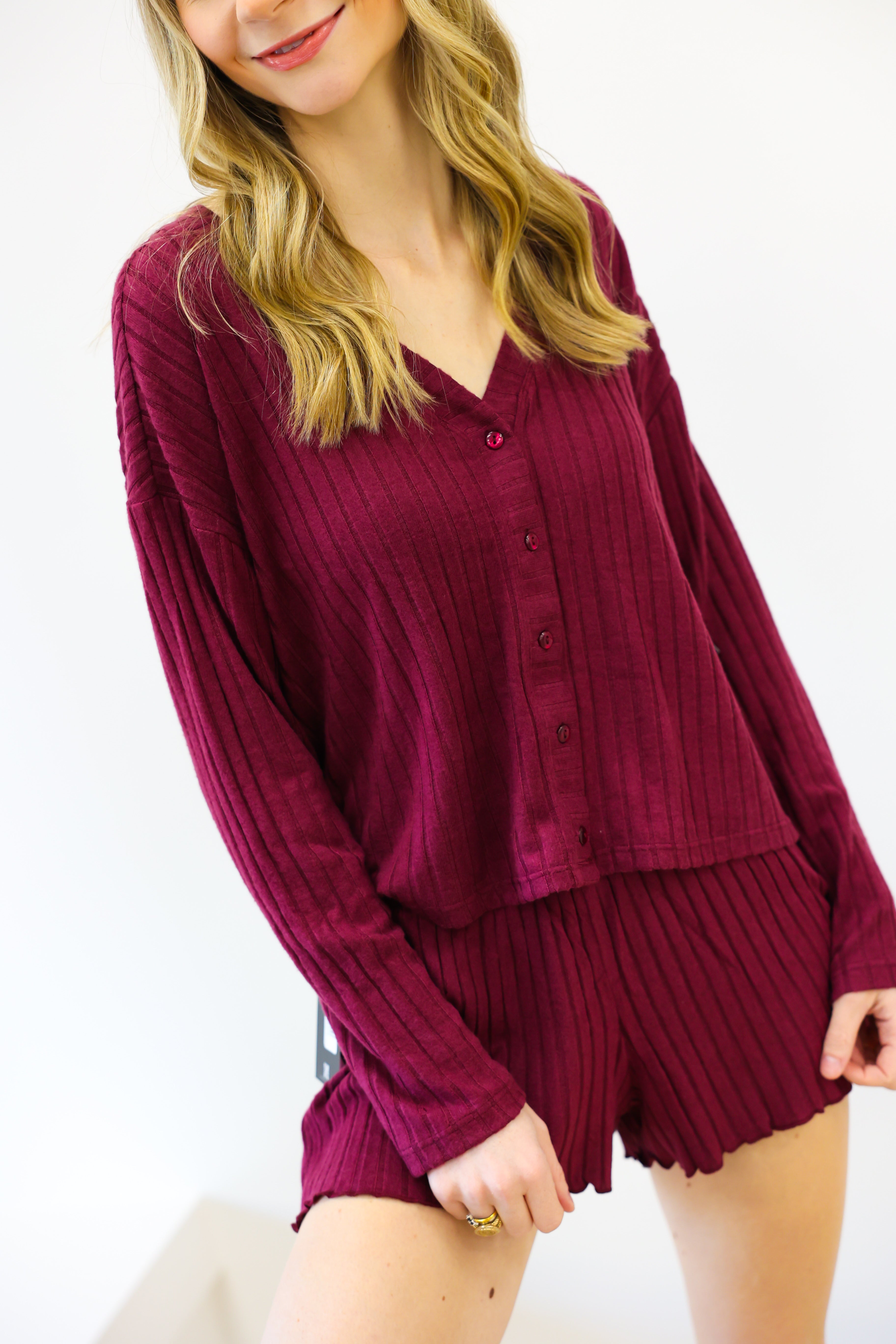 Woman wearing a burgundy ribbed lounge set on a white background