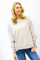 Woman wearing a beige sweater and blue jeans on a white background