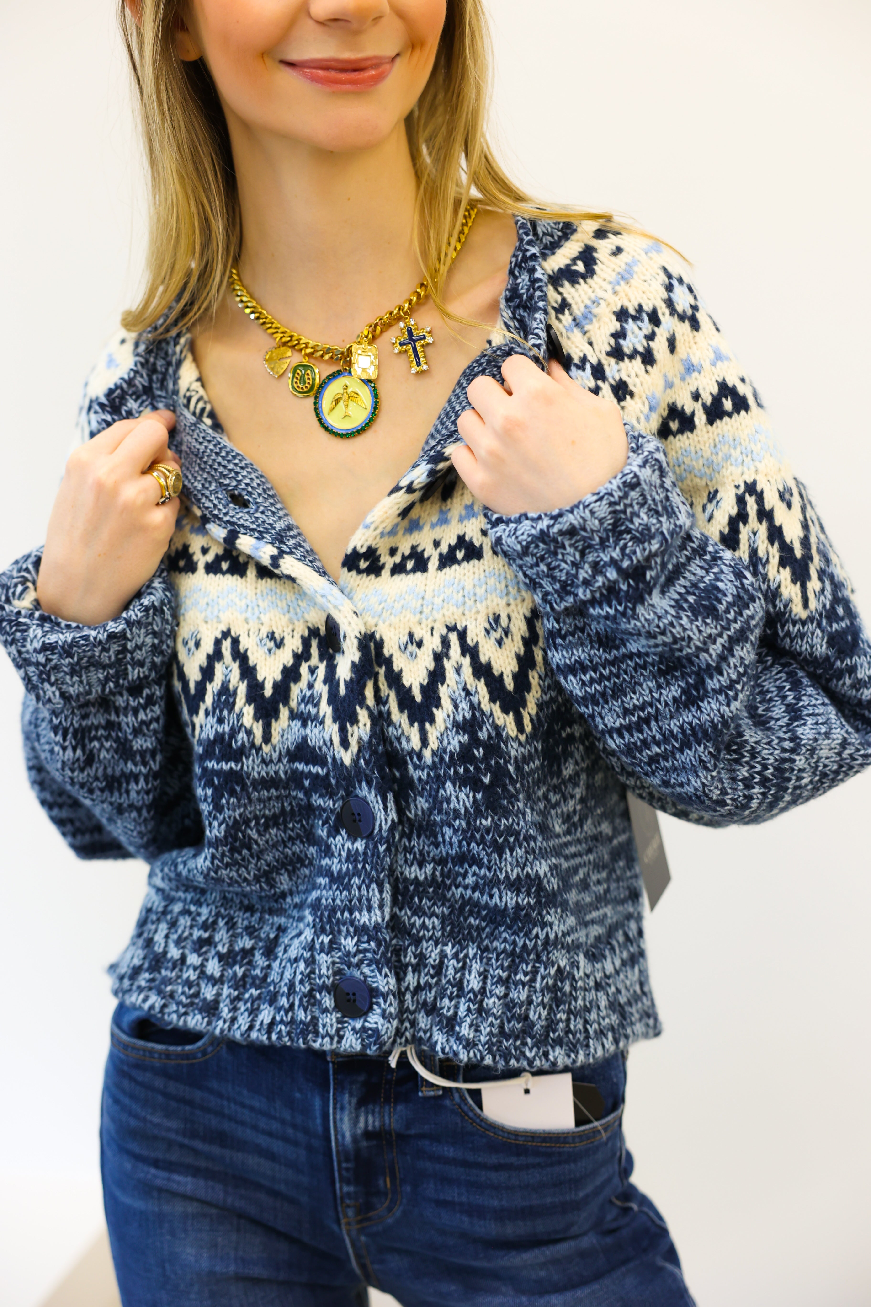 Person wearing a blue patterned cardigan with a plain background