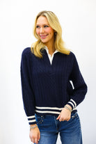 Woman wearing a navy sweater with white accents on a plain background