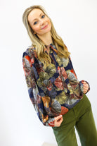 Woman wearing a colorful patterned shirt and green pants on a white background