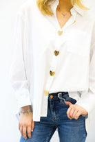 White blazer with gold buttons worn by a person, paired with blue jeans on a white background