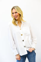 Woman wearing a white blouse with gold buttons on a white background