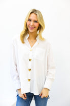 Woman wearing a white blouse with gold buttons on a white background