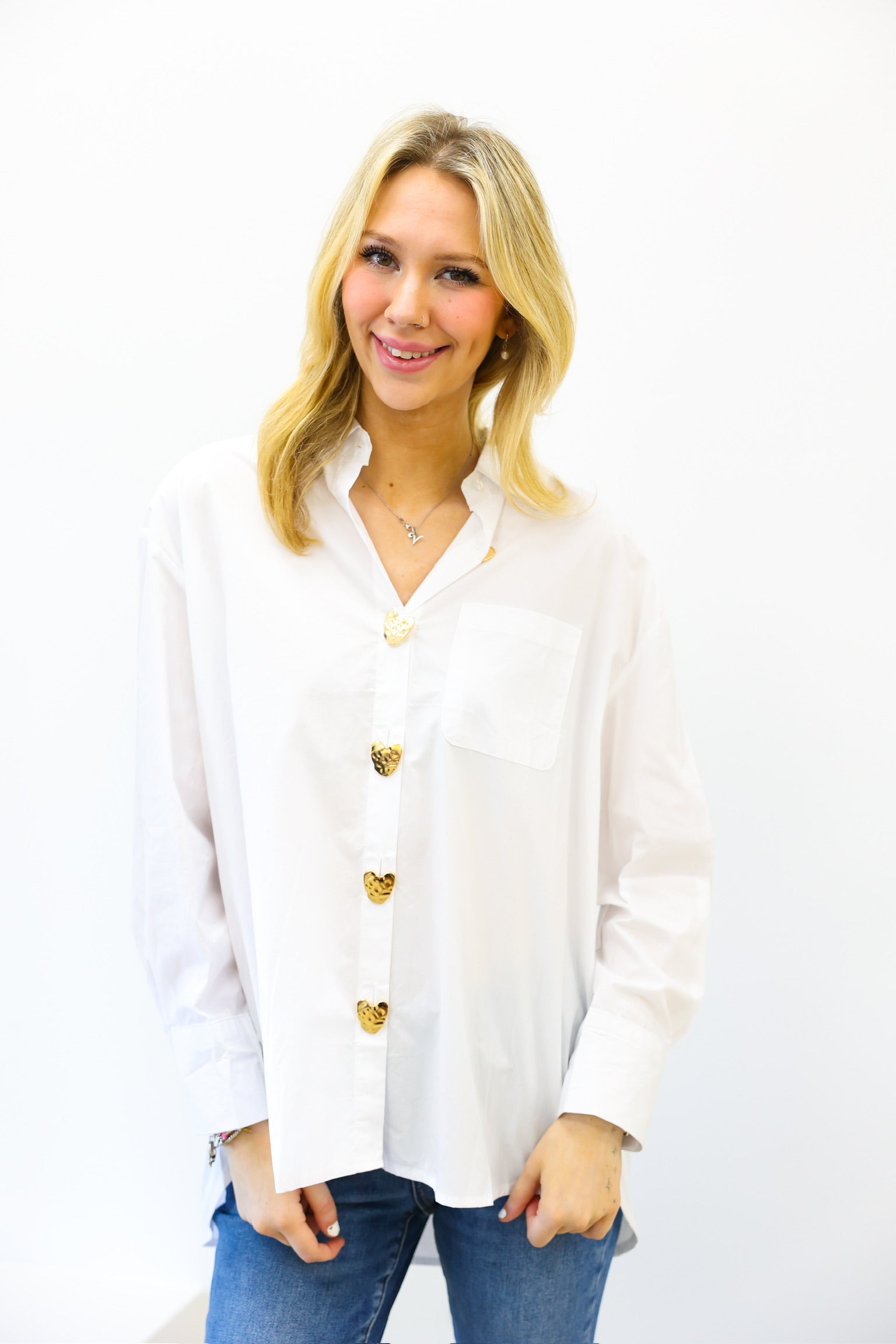 Woman wearing a white blouse with gold buttons on a white background