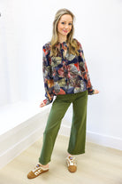 Woman wearing a colorful blouse and green pants on a white background