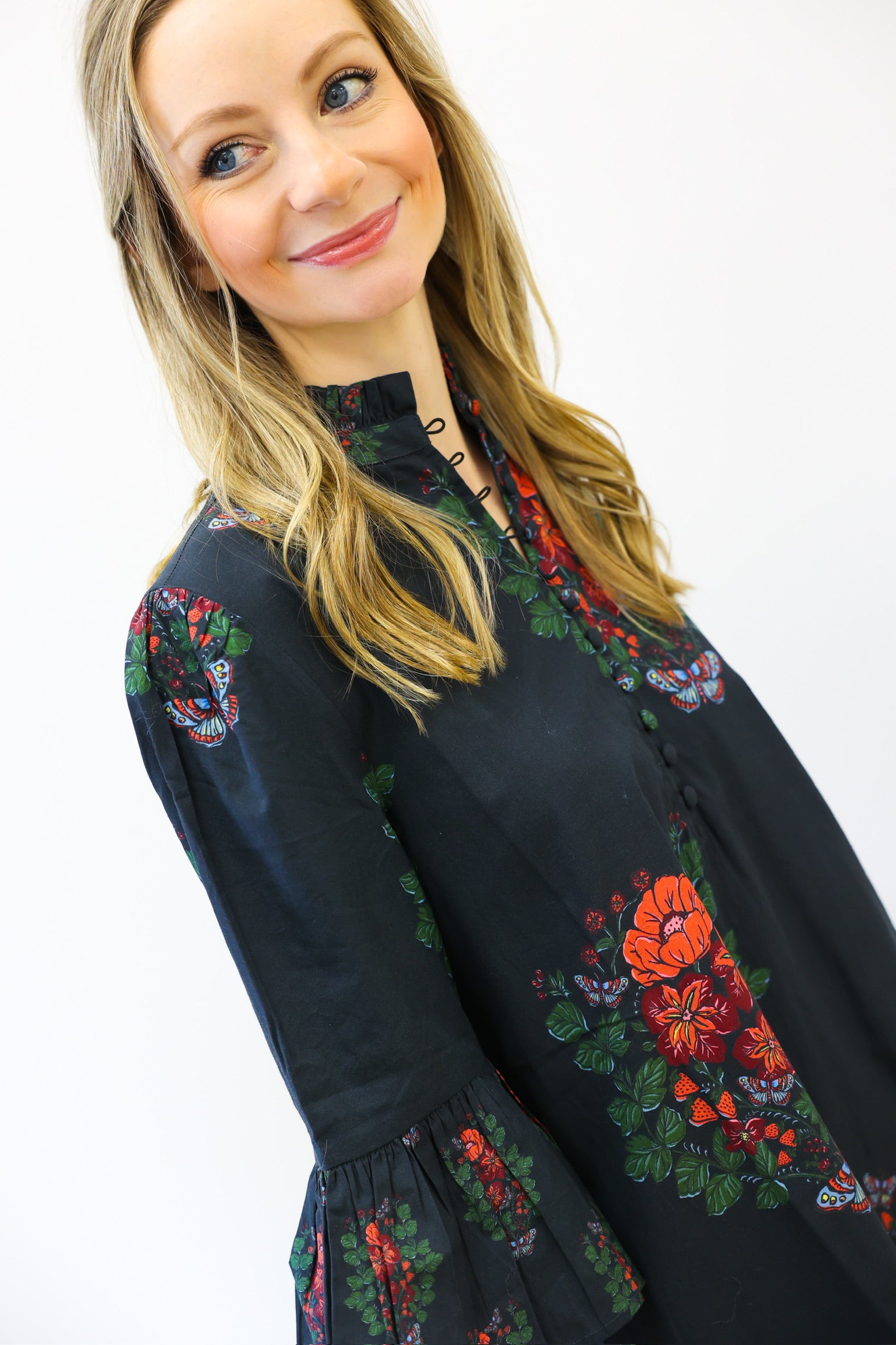 Woman wearing a black dress with colorful floral embroidery on a white background