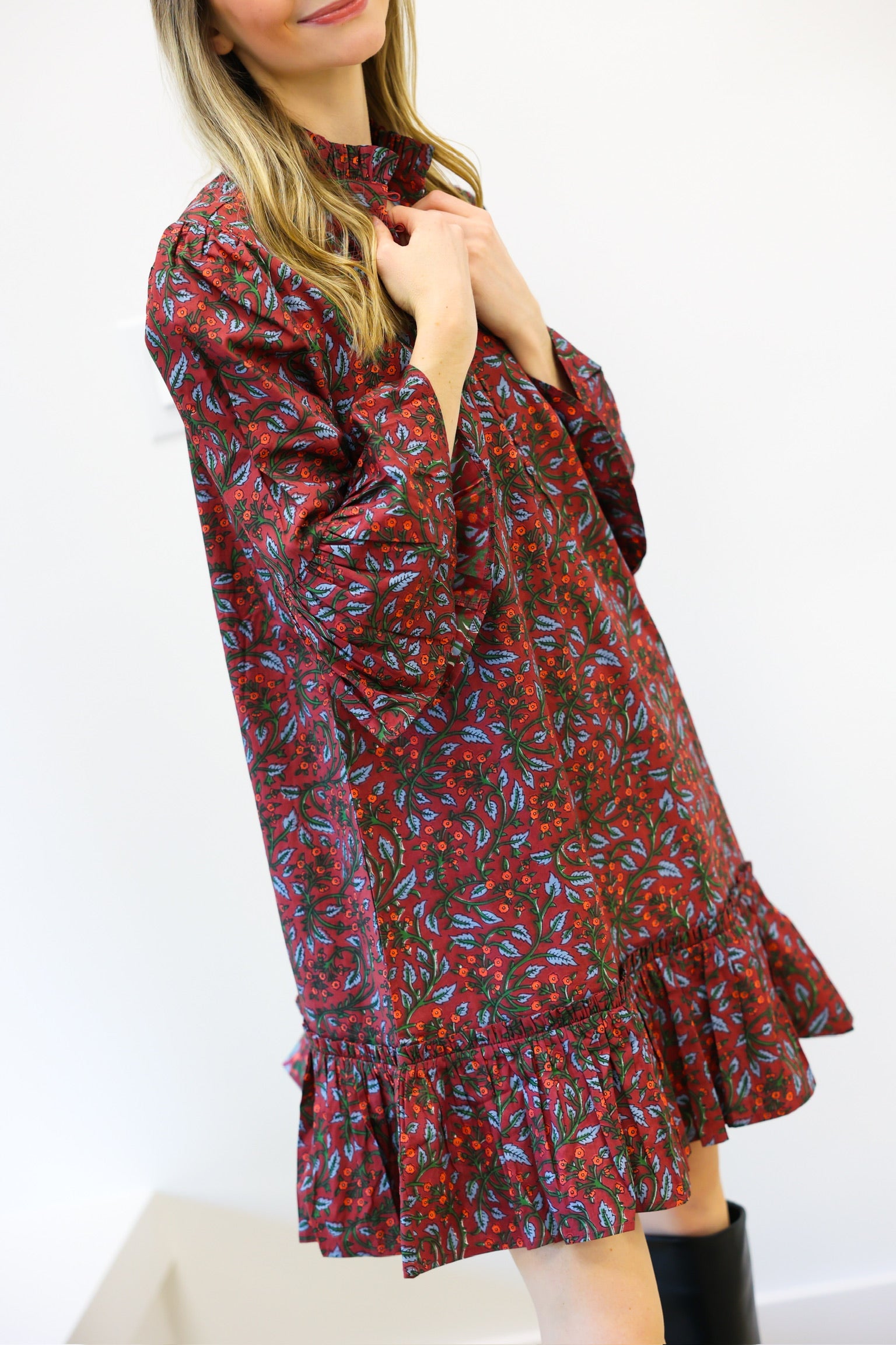 Woman wearing a red floral dress with long sleeves on a white background