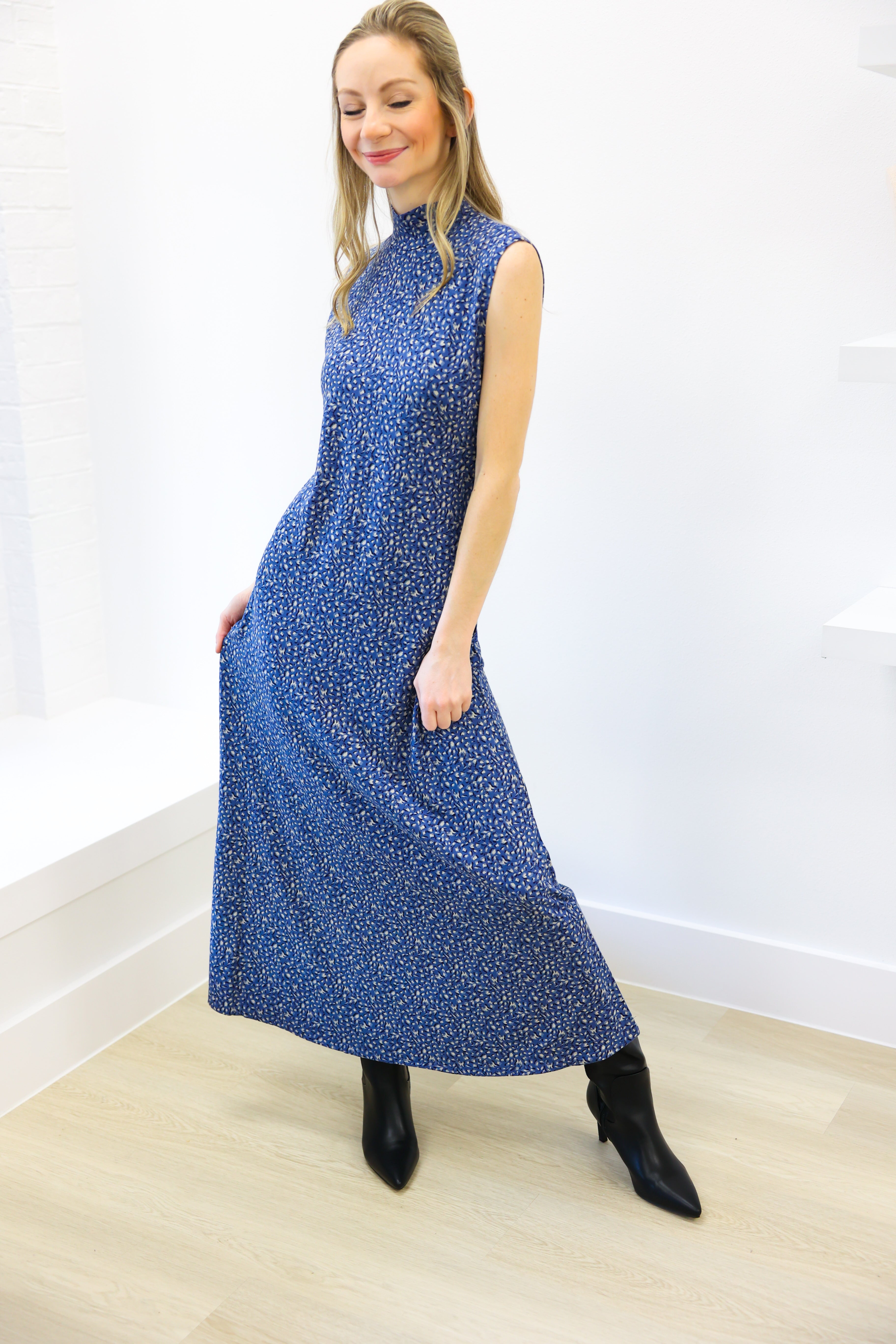 Woman wearing a blue sleeveless dress with a white pattern on a white background