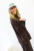 Woman wearing a brown sweater and pants with a cap on a white background