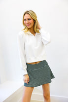 Woman wearing a white blouse and striped skirt against a white background
