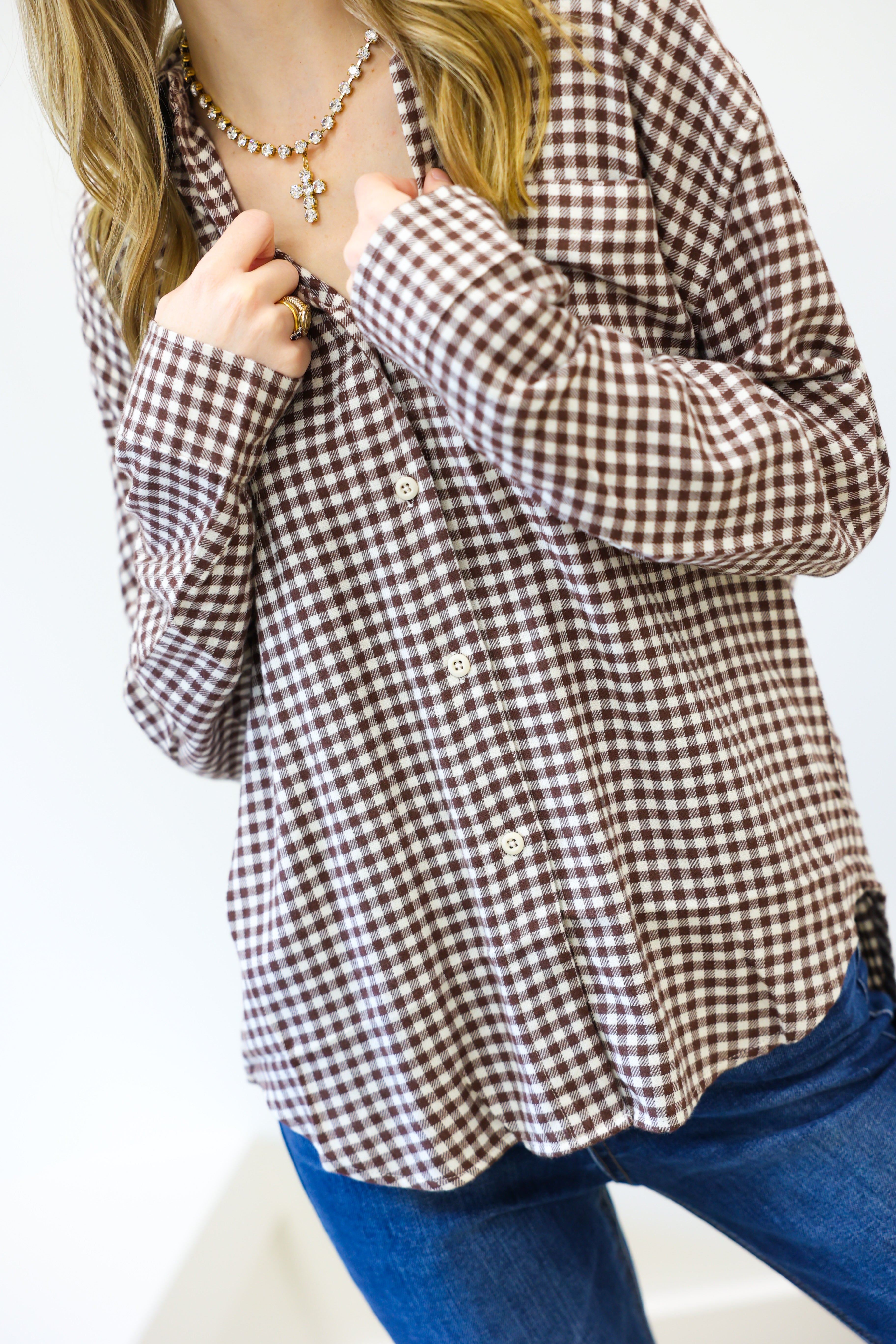Person wearing a brown and white checkered shirt with blue jeans on a white background