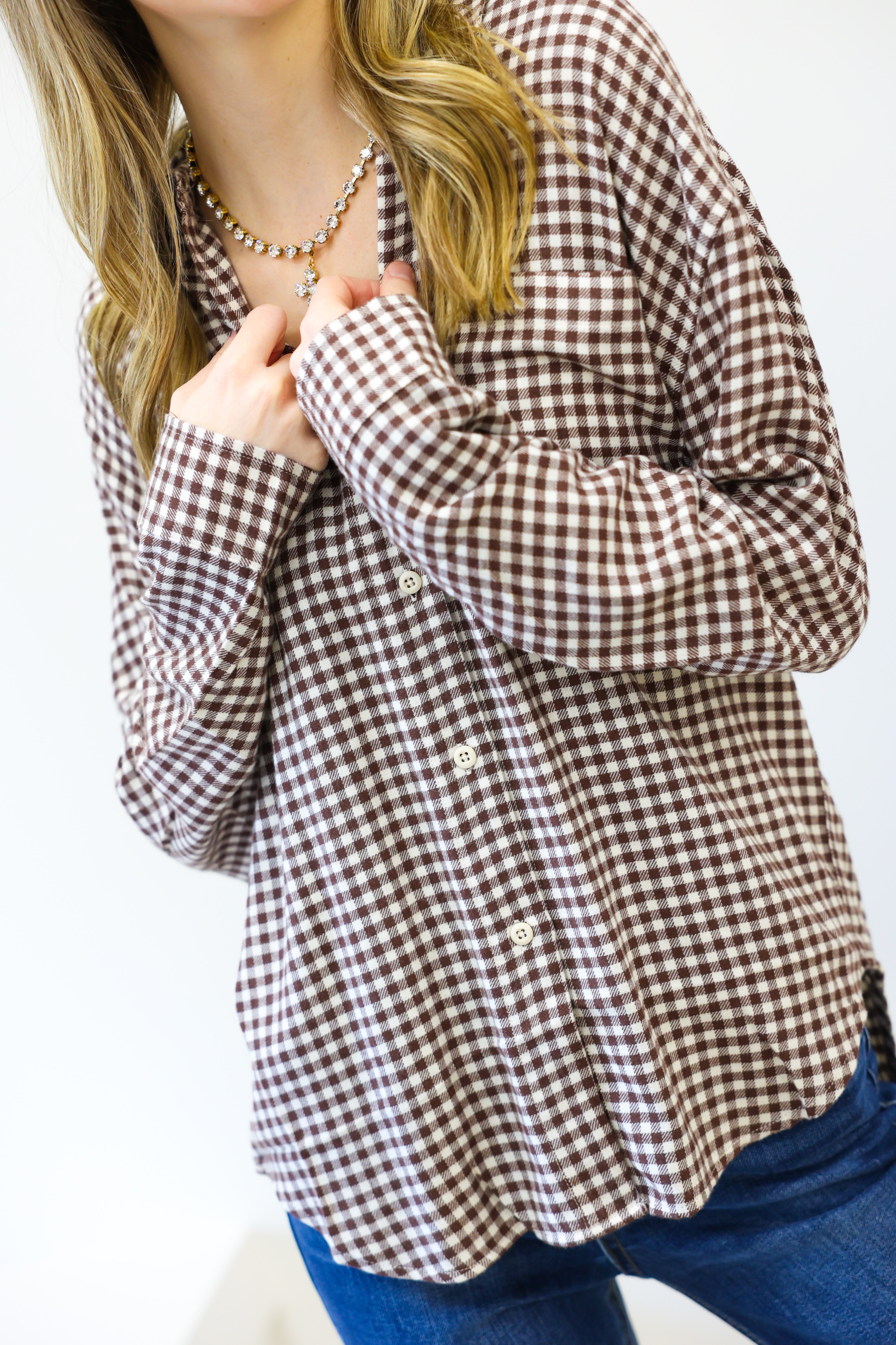 Person wearing a brown and white checkered shirt with a plain background