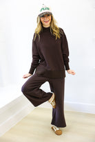 Person wearing a brown outfit with a white wall background