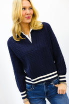 Woman wearing a navy sweater with white stripes and blue jeans on a white background