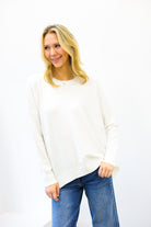 Woman wearing a white sweater and blue jeans on a white background