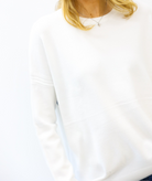 White sweatshirt worn by a person with blonde hair, on a white background