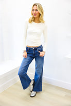 Woman wearing a white top and blue jeans against a white background