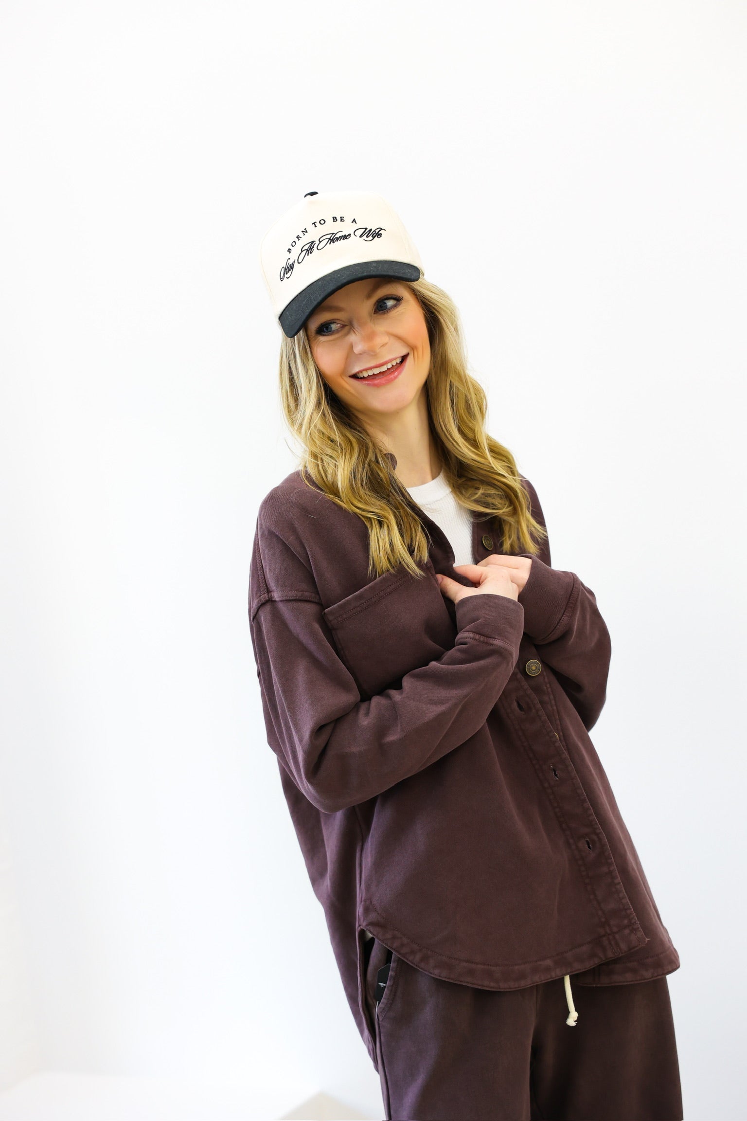 Person wearing a brown jacket and cap on a white background
