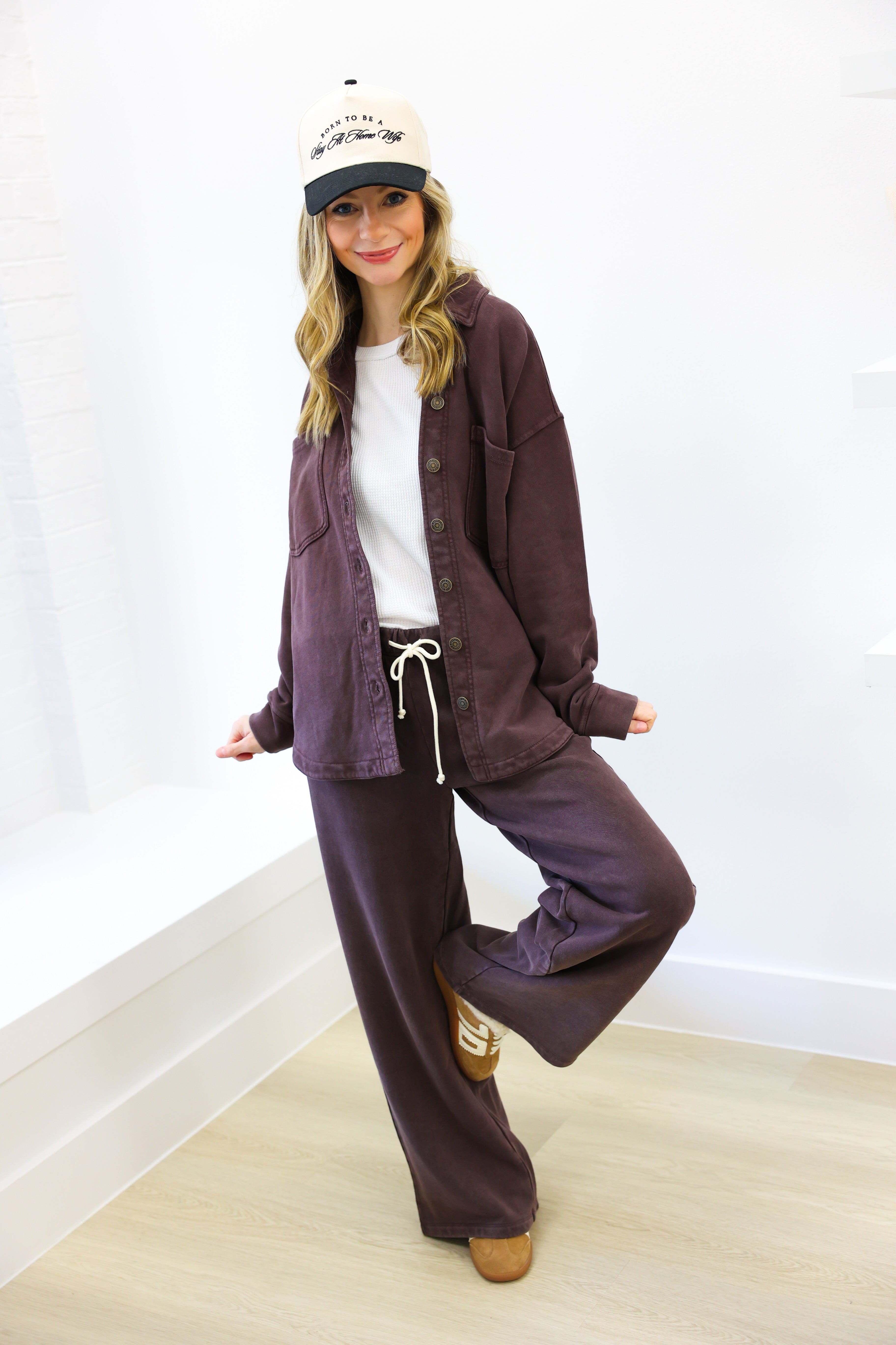 Person wearing a purple tracksuit and white cap against a white background