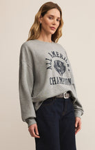 Woman wearing a gray sweatshirt with text and graphics on a plain background