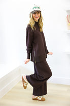 Person wearing a brown outfit with a cap, standing on a light wooden floor.