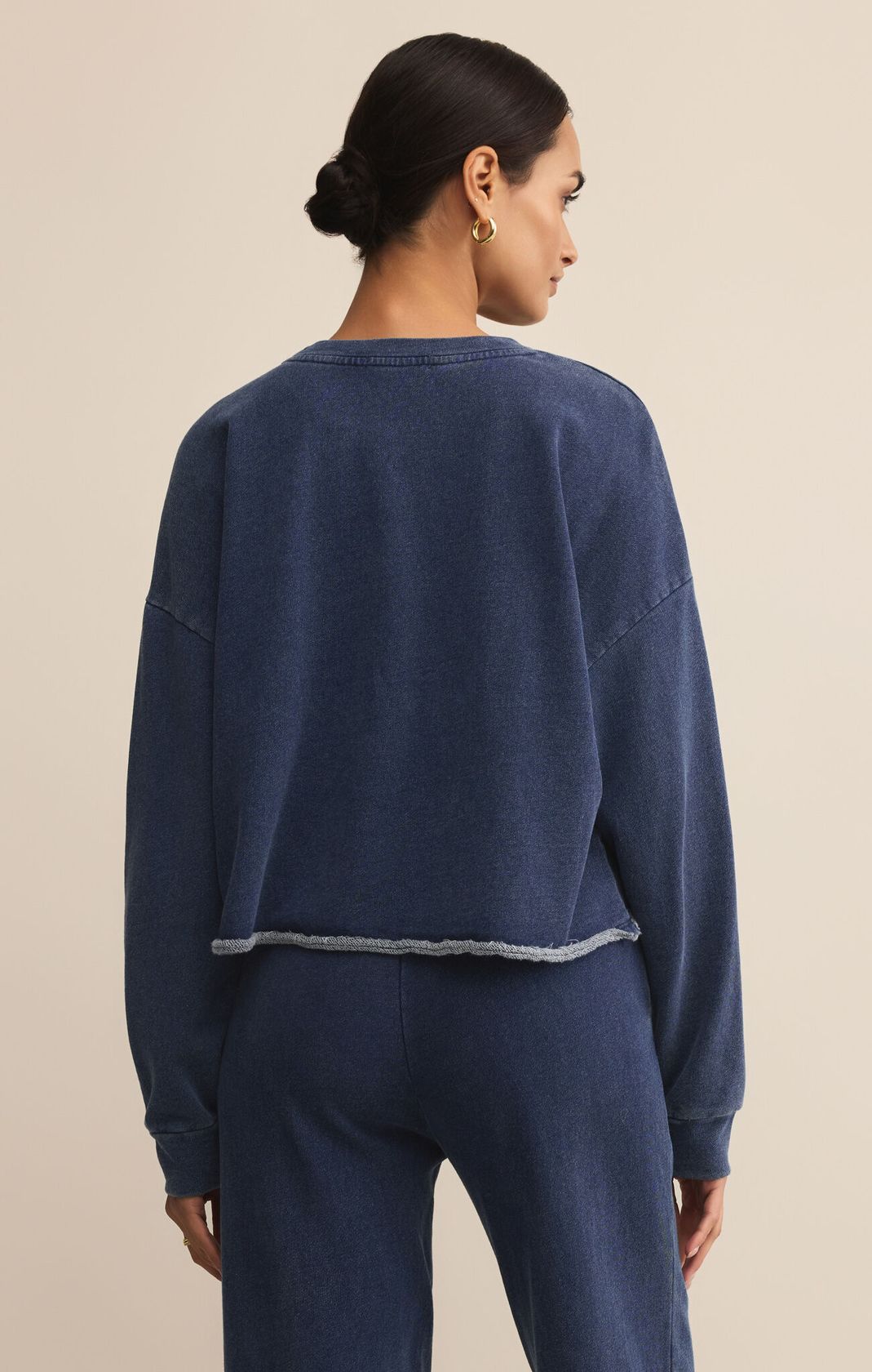 Woman wearing a navy blue sweatshirt and pants on a beige background