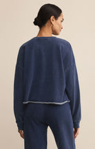 Woman wearing a navy blue sweatshirt and pants on a beige background